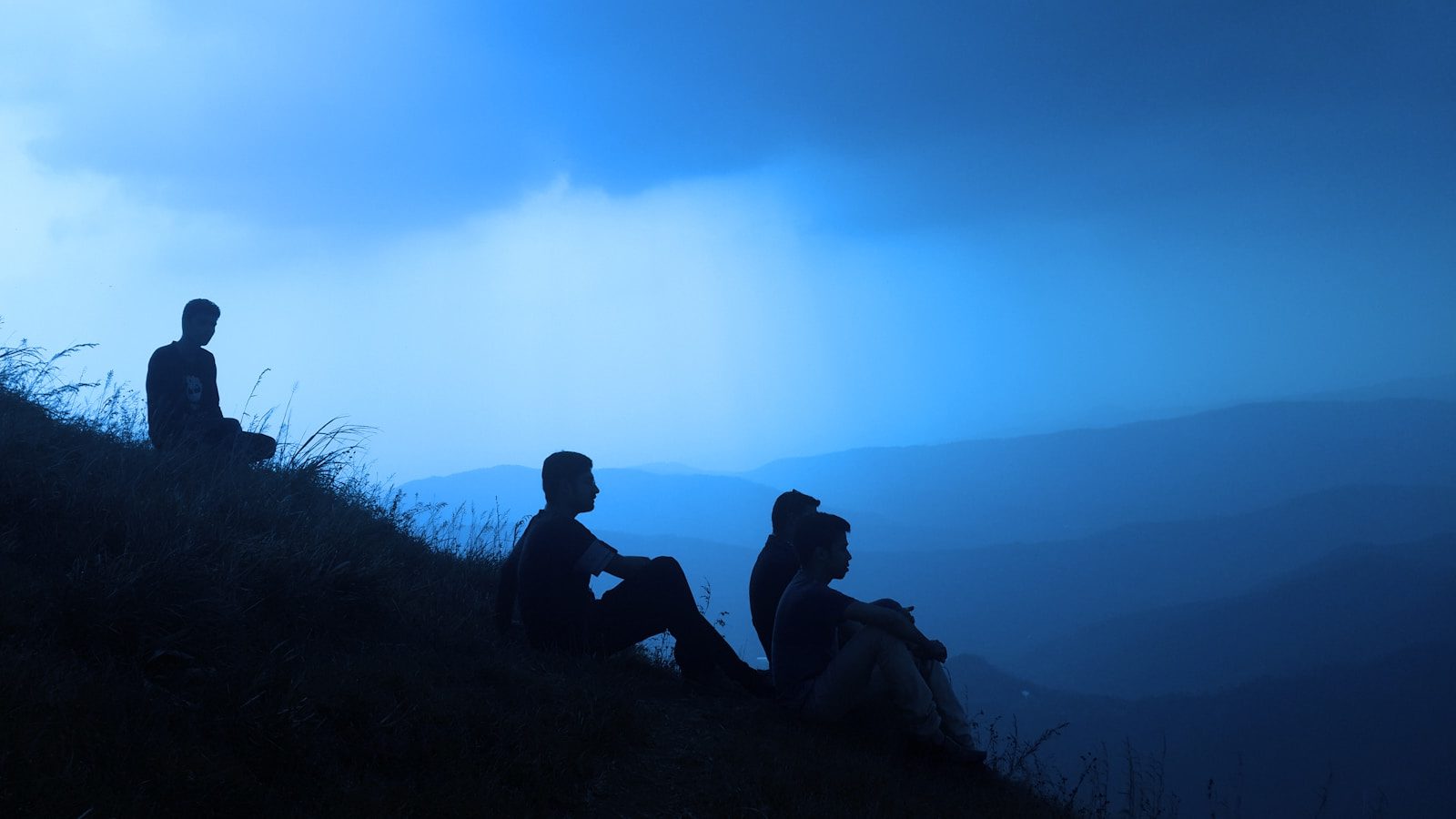 silhouette of men sitting on mountain